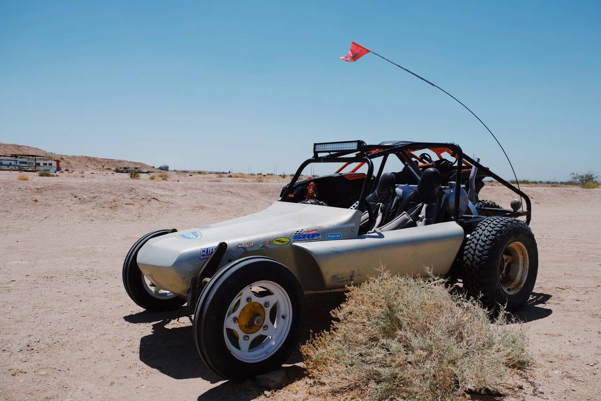 Dune Buggy Rentals parked on red sand dunes with drivers wearing helmets and goggles